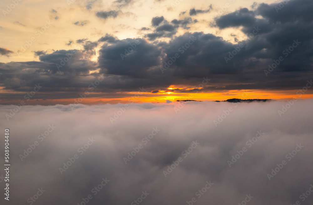 Obraz premium aerial view over the clouds during sunrise. Golden hour and amazing sunrays, beautiful cloudscape. Picturesque of white fluffy clouds moving softly on cloudy, misty weather.