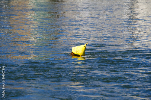 Moored yellow buoy swimming on Rhine River on a sunny spring day. Photo taken May 11th, 2022, Basel, Switzerland. photo