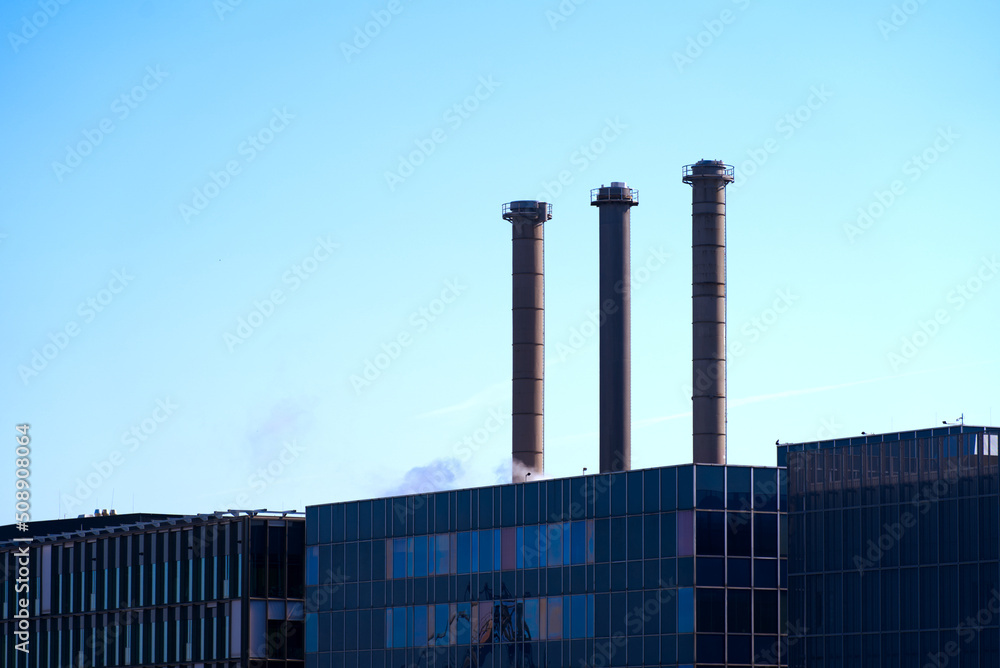 Facades of factory buildings with tree chimneys in backlight at industrial district of City of Basel on a sunny spring day. Photo taken May 11th, 2022, Basel, Switzerland. Facades of factory buildings with tree chimneys in backlight at industrial district of City of Basel on a sunny spring day. Photo taken May 11th, 2022, Basel, Switzerland.