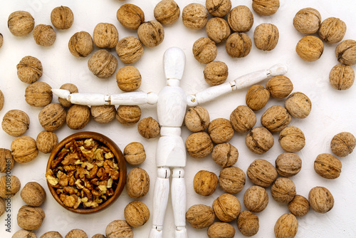 Wooden mannequin with walnuts white background. The human brain is shaped like a walnut kernel.