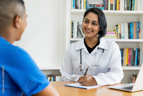 Laughing hispanic female doctor  talking with healthy patient