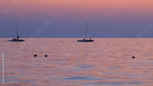 sailboats in a calm sea at sunset