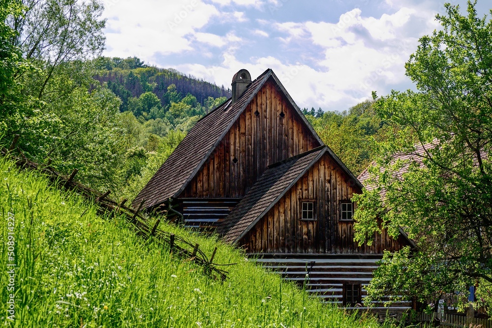 Obraz premium A timbered house with a interesting double roof located in the village of Zubrnice, open-air museum, Czechia, in the romantic hilly countryside