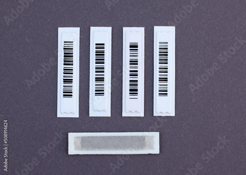 Plastic White Barcode Soft Tags on gray background. Magnetic AM label with barcode: the necessary protection even for small products. Retail security.