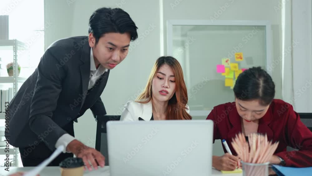 Asian business team looking at computers and talk about intense work in the office Asian business team looking at computers and talk about intense work in the office