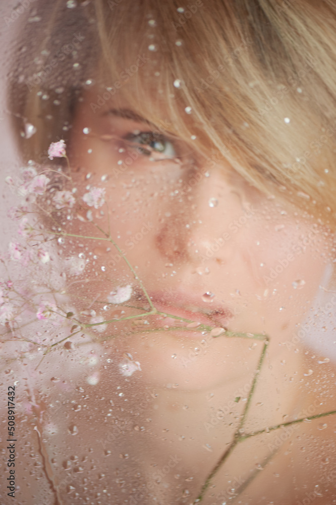 Fototapeta premium A gentle girl on a pink background, behind fogged glass. Femininity and tenderness, relaxation. Beauty and personal care industry.