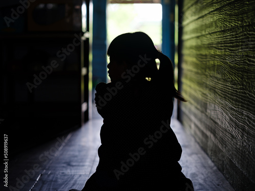Print op canvas Sad lonely little girl crying while sitting on the floor in dark room with an attitude of sadness
