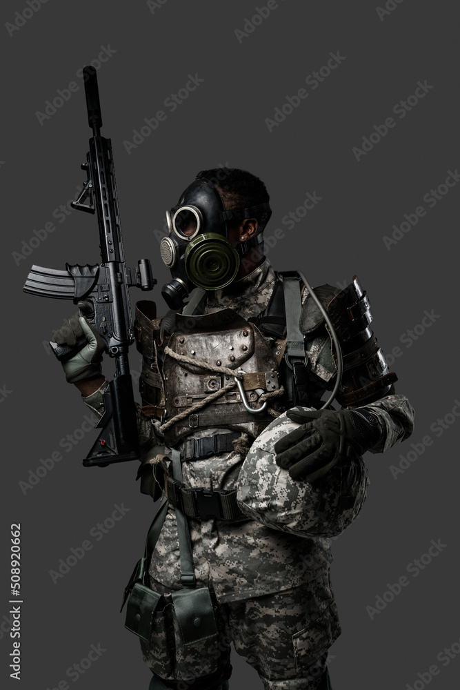Studio shot of black military man with gas mask holding looking away against grey background. Studio shot of black military man with gas mask holding looking away against grey background.