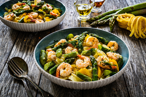 Tagliatelle with prawns and asparagus on wooden table
 photo