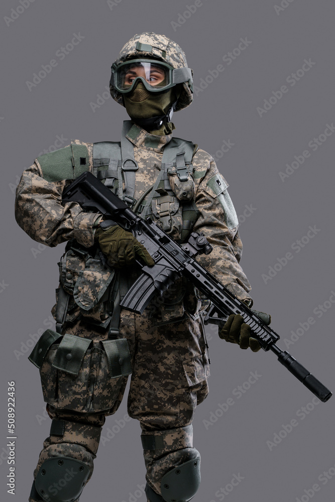 Portrait of professional servicewoman with rifle dressed in camouflage clothes against grey background. Portrait of professional servicewoman with rifle dressed in camouflage clothes against grey background.