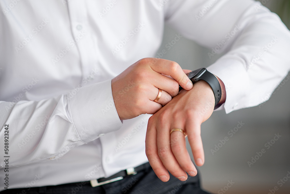hands of the groom in a white shirt with a watch and a ring. fees for work or wedding. close-up hands of the groom in a white shirt with a watch and a ring. fees for work or wedding. close-up