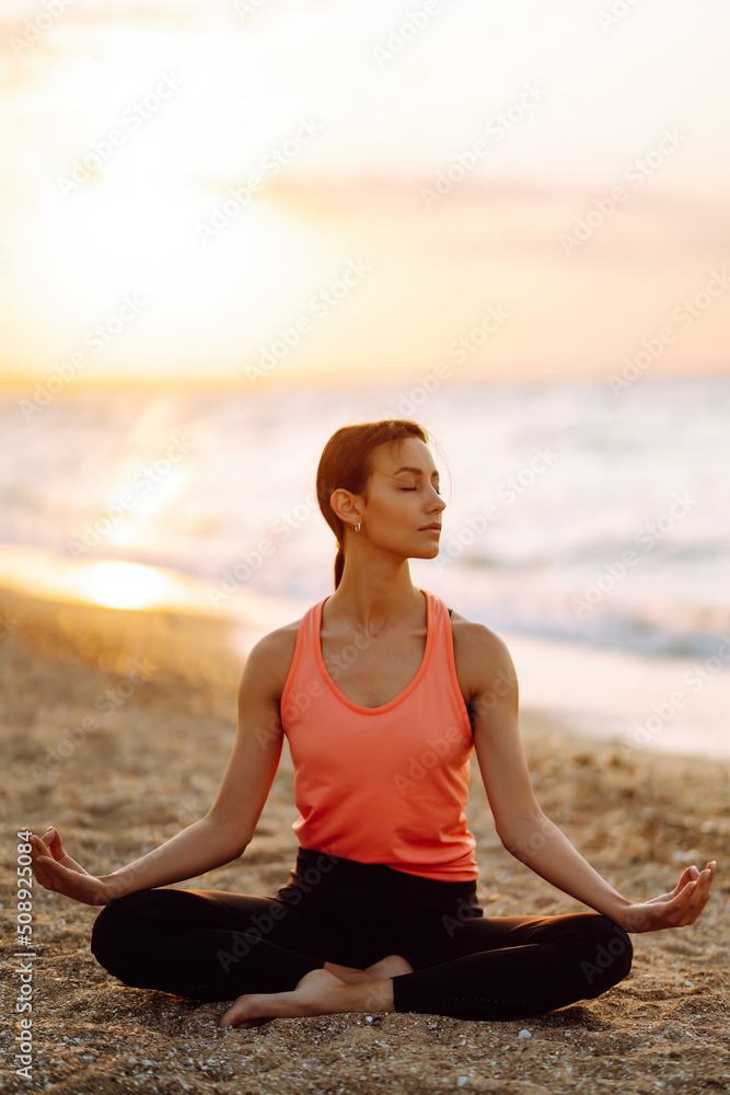 Young beautiful woman practices yoga and meditates on the beach. Sport, Active life. 