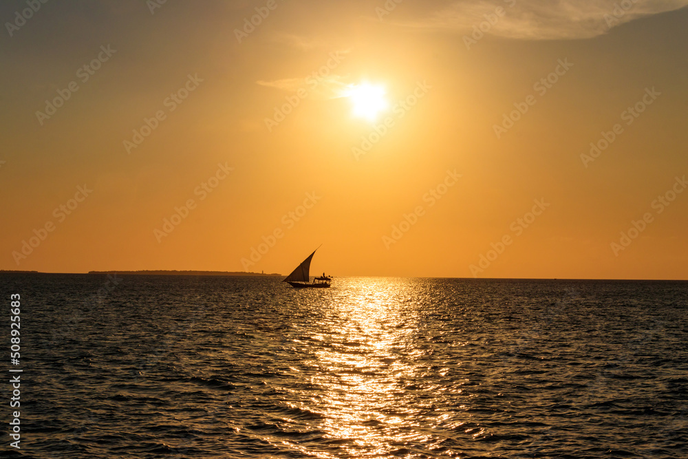Silhouette of traditional wooden dhow boat in the Indian ocean at sunset in Zanzibar, Tanzania