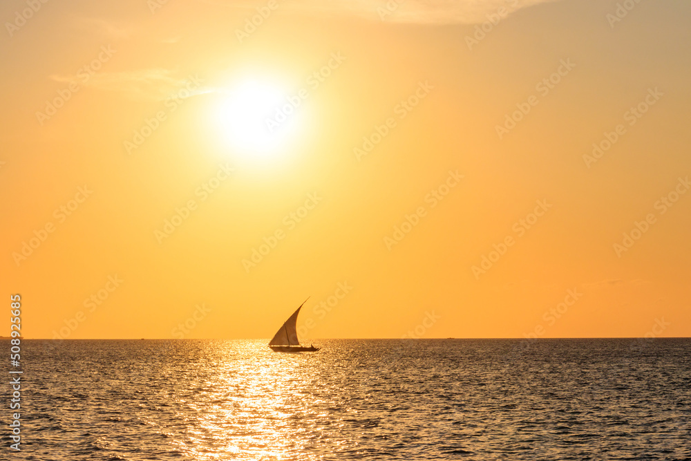 Silhouette of traditional wooden dhow boat in the Indian ocean at sunset in Zanzibar, Tanzania