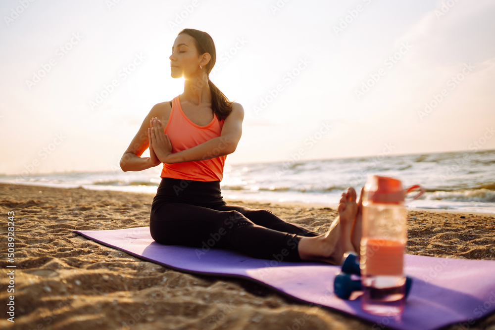 Fototapeta premium Young woman in sportswear doing yoga, fitness exerciseon the beach. Sport, Active life. 