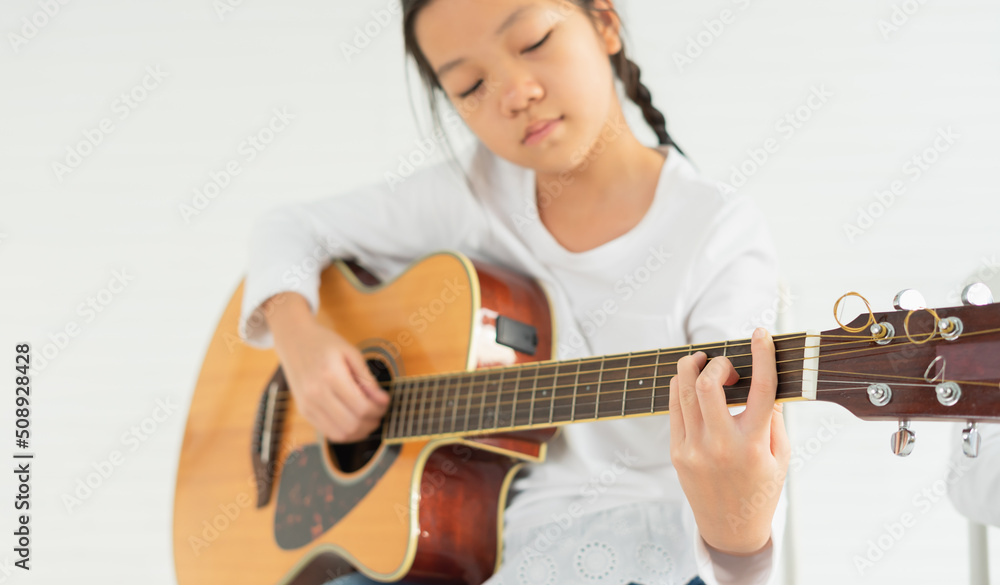 beautiful young children show playing guitar, look at finger. asian children study and learn musical and singing in education classroom at small school beautiful young children show playing guitar, look at finger. asian children study and learn musical and singing in education classroom at small school