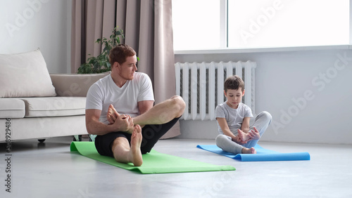 Father and Son do Spotting. Sport at Home. Warm Up in Quarter. Lying on Gymnastic Mat. Doing Sports. Man and Boy Train at Home.