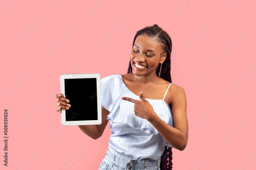 Charming young black woman showing tablet with empty screen on pink background, mockup for website or new app Charming young black woman showing tablet with empty screen on pink background, mockup for website or new app