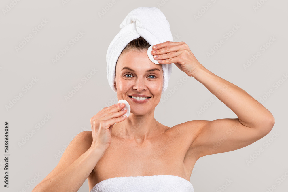 Middle Aged Woman With Towel On Head Clensing Skin With Cotton Pads Middle Aged Woman With Towel On Head Clensing Skin With Cotton Pads