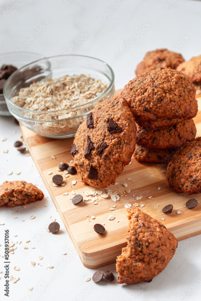 Fototapeta premium High view of homemade oat cookies with chocolate. Healthy breakfast served on wood board. Rustic snack for a healthy lifestyle.
