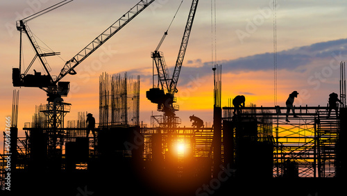 Silhouette of Engineer and worker on building site, construction site at sunset in evening time