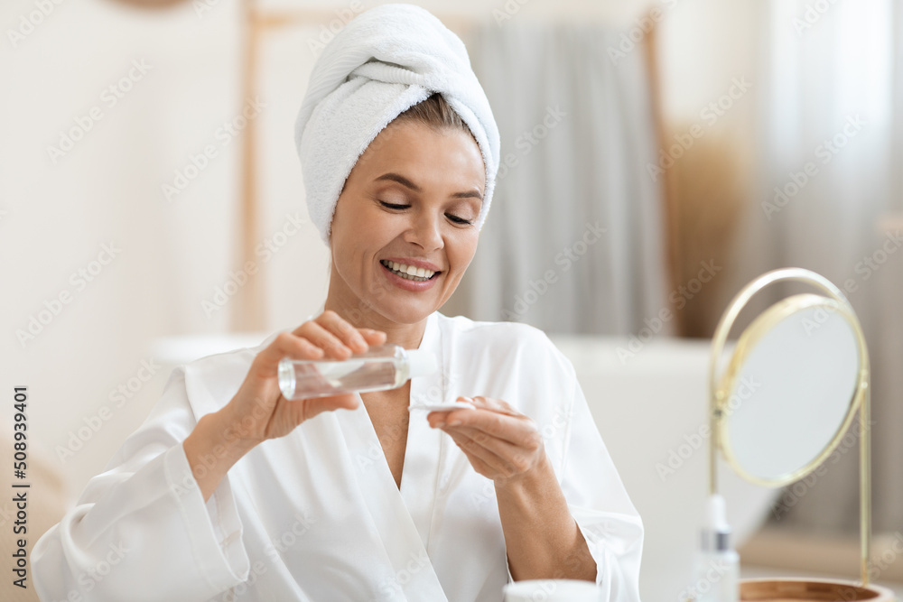 Attractive middle aged woman using face tonner and cotton pads Attractive middle aged woman using face tonner and cotton pads