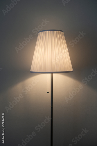 Standing floor table lamp with light shining through the lampshade photo