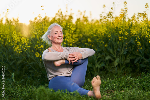 Senior lady yoga workout by canola field