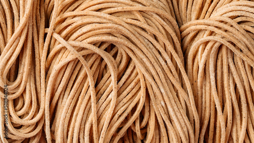 Closeup on dry raw buckwheat noodles texture background