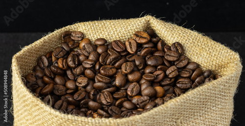 freshly picked coffee beans inside the sack, black background © Brukoikstudy