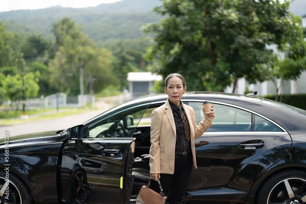 Asian mature woman disembarking the luxury car