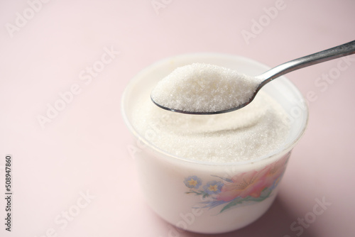 white sugar and spoon in a container on black background,