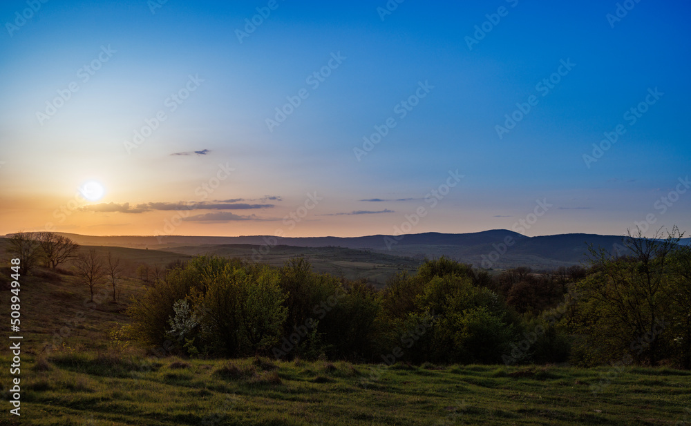 Field with plants in the valley against the backdrop of the sunset sky in Bulgaria