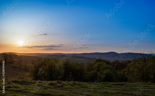 Field with plants in the valley against the backdrop of the sunset sky in Bulgaria