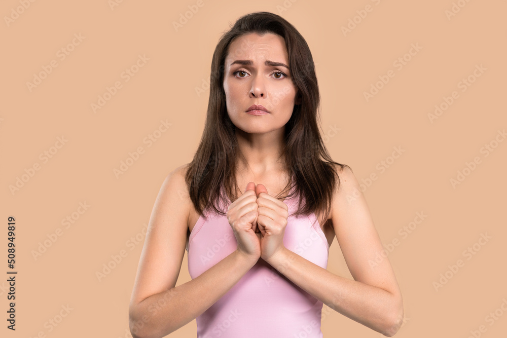 Asking help or praying worried woman with hands put together looking in camera with help need in her eyes. Hopeful religious woman in hope for forgiveness isolated on pink background Asking help or praying worried woman with hands put together looking in camera with help need in her eyes. Hopeful religious woman in hope for forgiveness isolated on pink background