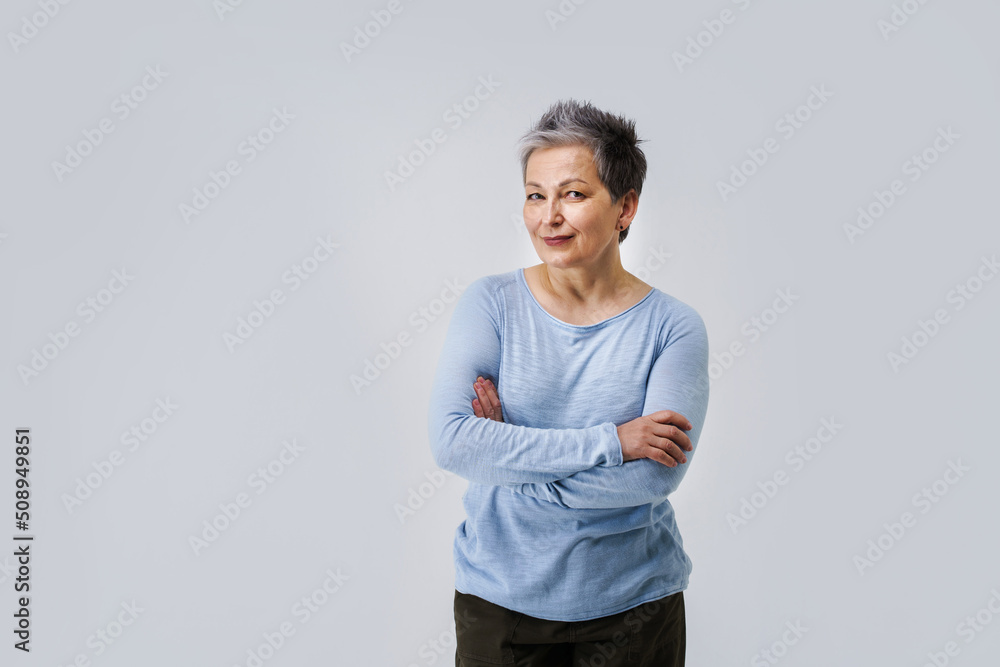 Lovely grey hair mature business woman in 50s posing sideways with hands folded and copy space on right isolated on white background. Copy space and place for product placement. Aged beauty Lovely grey hair mature business woman in 50s posing sideways with hands folded and copy space on right isolated on white background. Copy space and place for product placement. Aged beauty