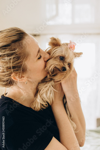 The owner kisses her pet yoksher terrier