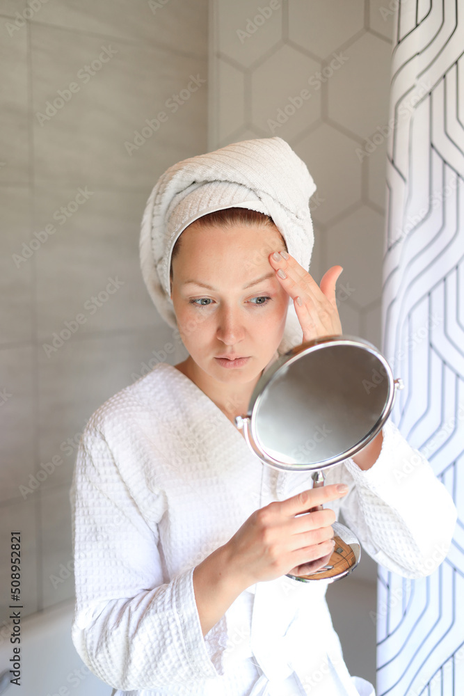 Anxious young woman looks in mirror, worries about facial wrinkles, thinks about facial injections, pensive frustrated has skin problems, needs skincare procedure from beautician Anxious young woman looks in mirror, worries about facial wrinkles, thinks about facial injections, pensive frustrated has skin problems, needs skincare procedure from beautician