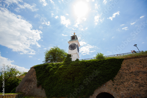 The Clock Tower, visual symbol of the Petrovaradin Fortress at Novi Sad, on Danube river shore. Travel destination Serbia. Sunny day. Sky with clouds in backgrounds. Serbia, Europe. © mitarart