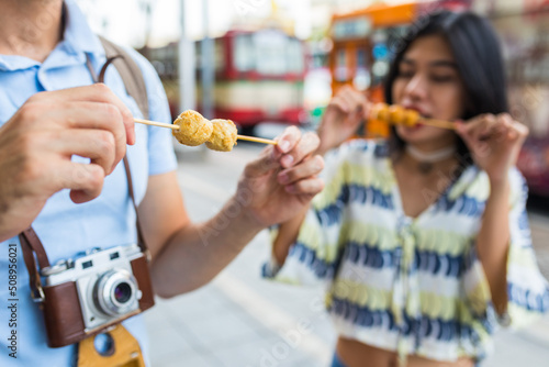 Close up of multiethnic friends eating street food in Bangkok