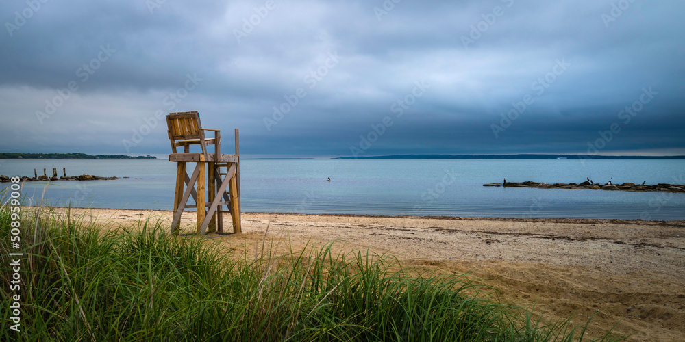 Lifeguard bench on the sandy beach on a cloudy empty bay on Cape Cod on a stormy day