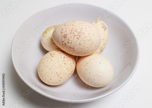 A bowl of fresh Turkey Eggs on a white background Large speckled eggs shells
