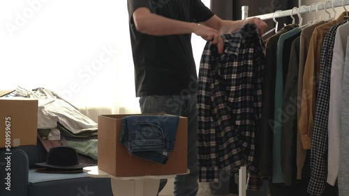 Young man decluttering his wardrobe and preparing to move. he chooses which clothes he wants to keep and which he wants to donate to charity. Home routine. He changes clothes from winter to summer. 4k
