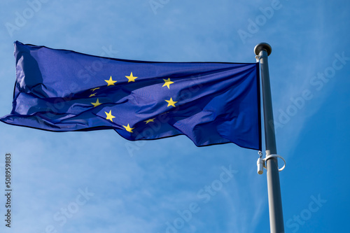 European union flag waving in the wind against blue sky.