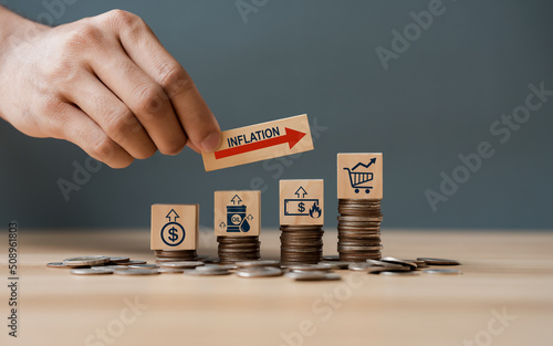 Hand putting wooden cube and inflation word a on coins in idea for FED consider interest rate hike, world economics, and inflation control, US dollar inflation photo