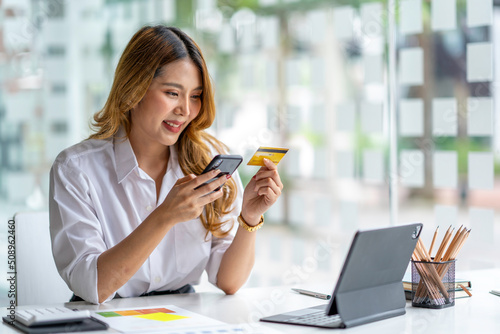 Young smiling asian woman resting and shopping online at home, Happy woman using laptop and credit card for online shopping. Online payment concept.