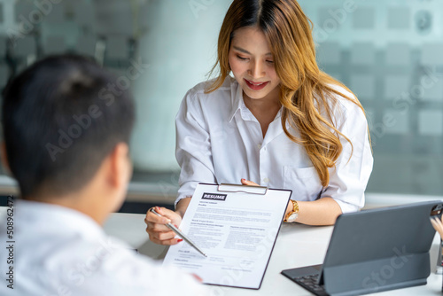Business, career and recruitment concept - young asian woman smiling and holding resume, while interviewing as candidate for job in big company