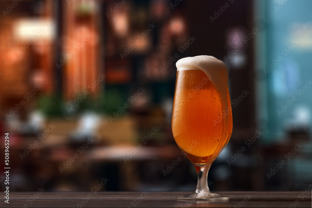 Tulip glass of beer on counter in pub. Tulip glass of beer on counter in pub.