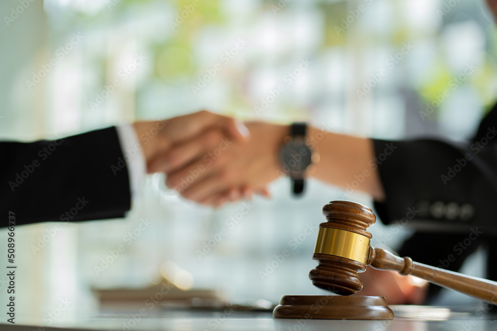 Businessmen and lawyers shake hands to discuss contract documents. Handshake advise after good cooperation Consultation between a male lawyer and a businessman client with a hammer in front. Businessmen and lawyers shake hands to discuss contract documents. Handshake advise after good cooperation Consultation between a male lawyer and a businessman client with a hammer in front.