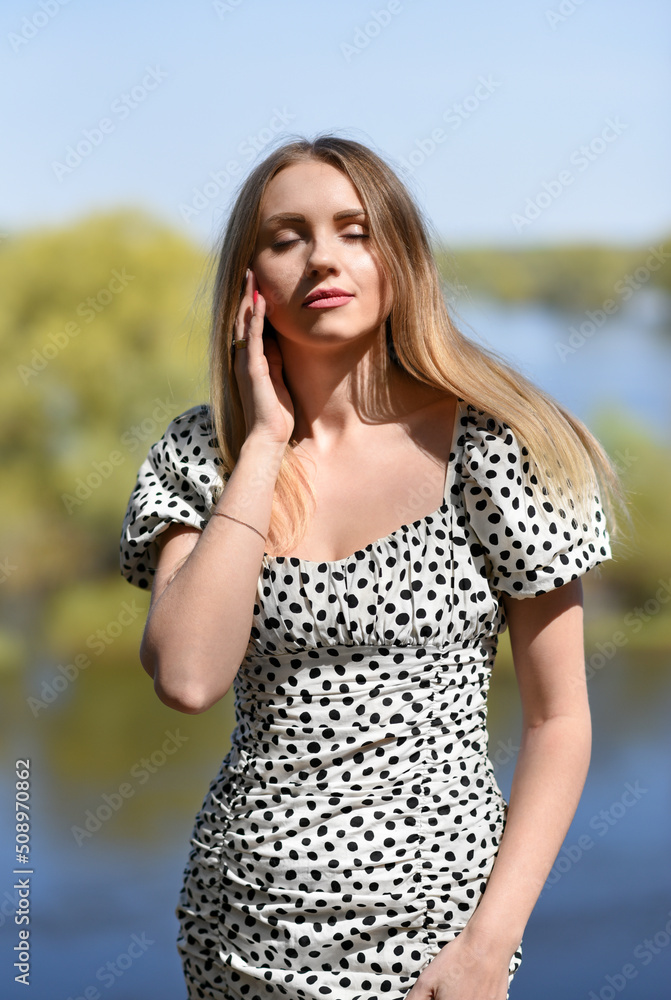 Girl with closed eyes stands on the background of the river